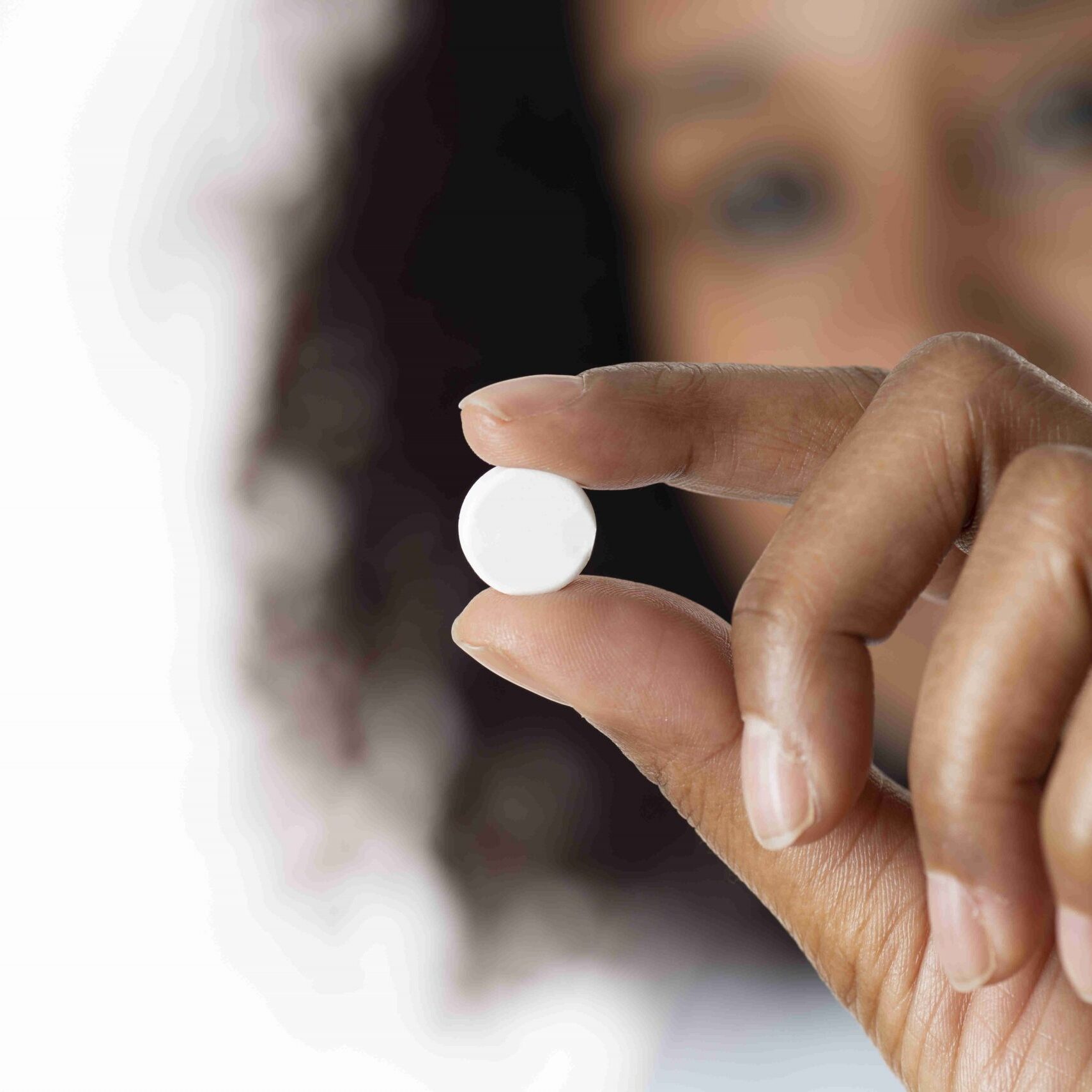 Close up photo of woman holding a white pill