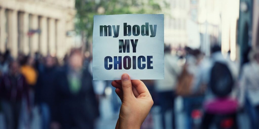 Person holding a paper saying "My body My choice"